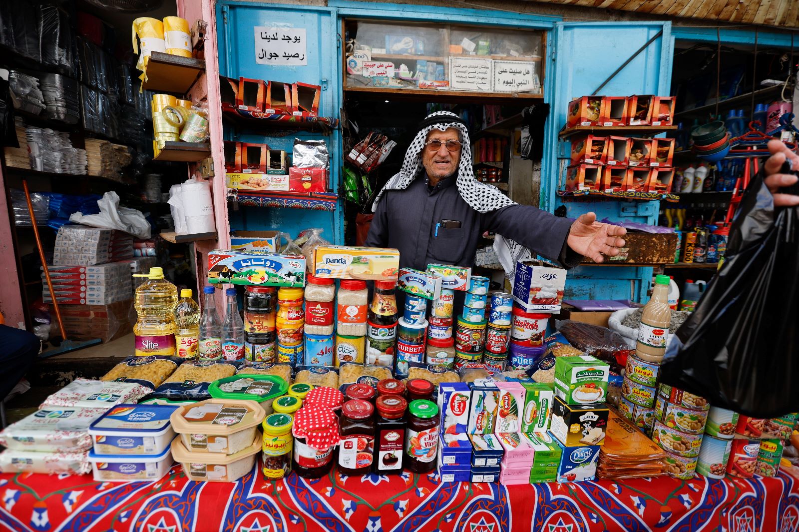بائع فلسطيني يعرض بضاعته من المواد الغذائية في إحدى الأسواق، قبيل شهر رمضان الماضي، آذار 2022.