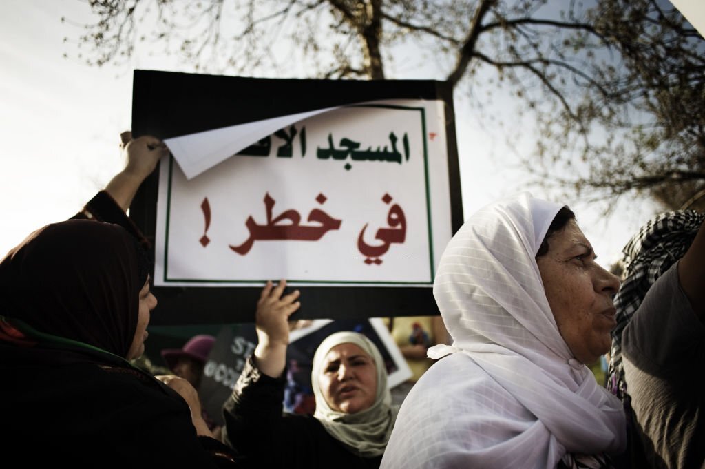 سيدة فلسطينية تحمل لافتة كتب عليها "المسجد الأقصى في خطر"، خلال اعتصام ضد الاستيطان في حيّ الشيخ جراح، مارس/ آذار 2010 (وكالة الصحافة الفرنسية).